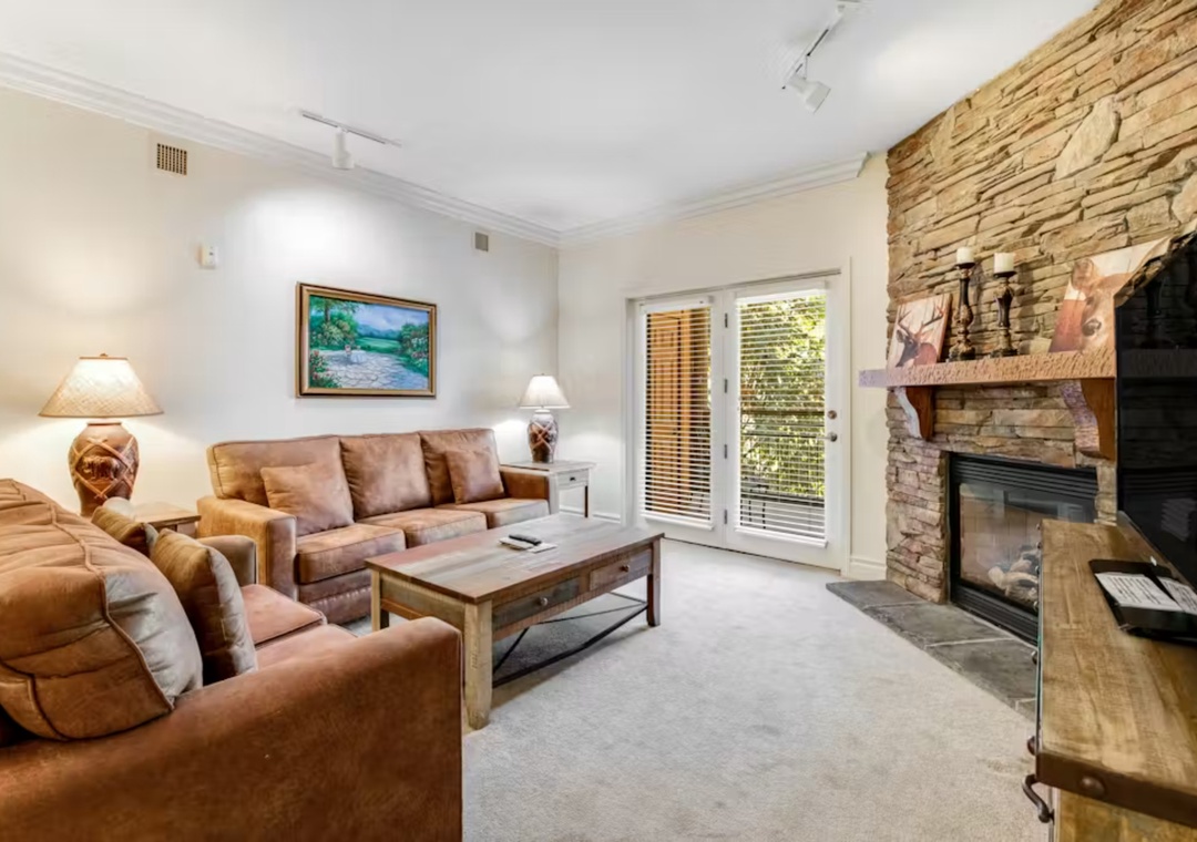 Sink into plush leather seating by your stone fireplace, where warm lighting and rustic charm create the perfect retreat for cozy evenings.