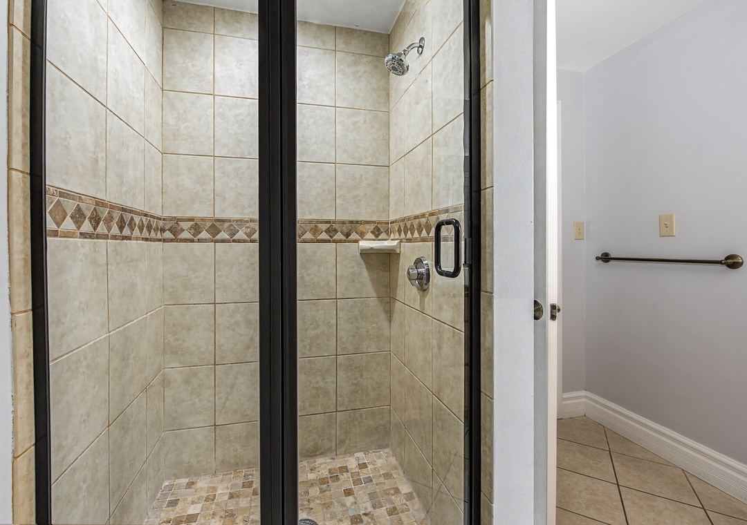 Step into your private sanctuary with elegant tiled shower featuring rainfall showerhead and designer mosaic details.