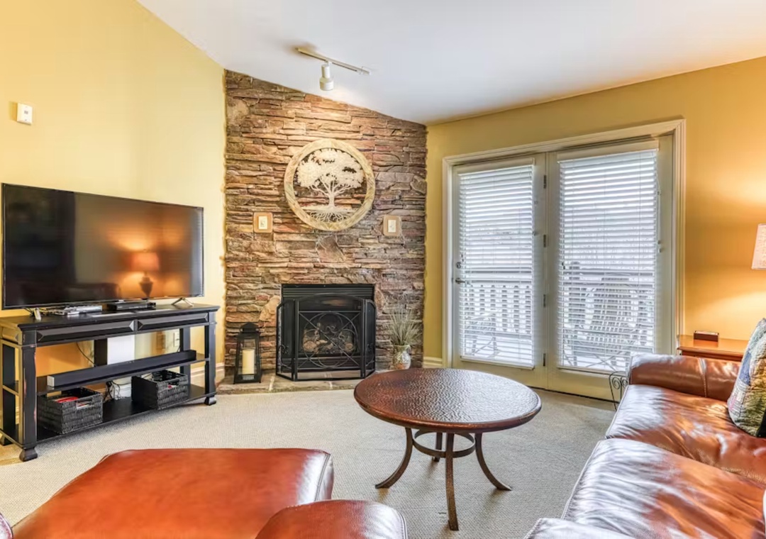 Unwind in your cozy living room with rich leather seating, stone fireplace, and modern entertainment center creating the perfect space to relax.