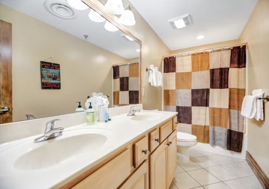 Your private bathroom offers a relaxing retreat with warm wood vanity, spacious shower-tub combo, and thoughtful touches like plush towels.