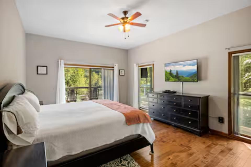 Wake up to forest views through expansive windows in your serene bedroom, complete with ceiling fan and smart TV for ultimate comfort.