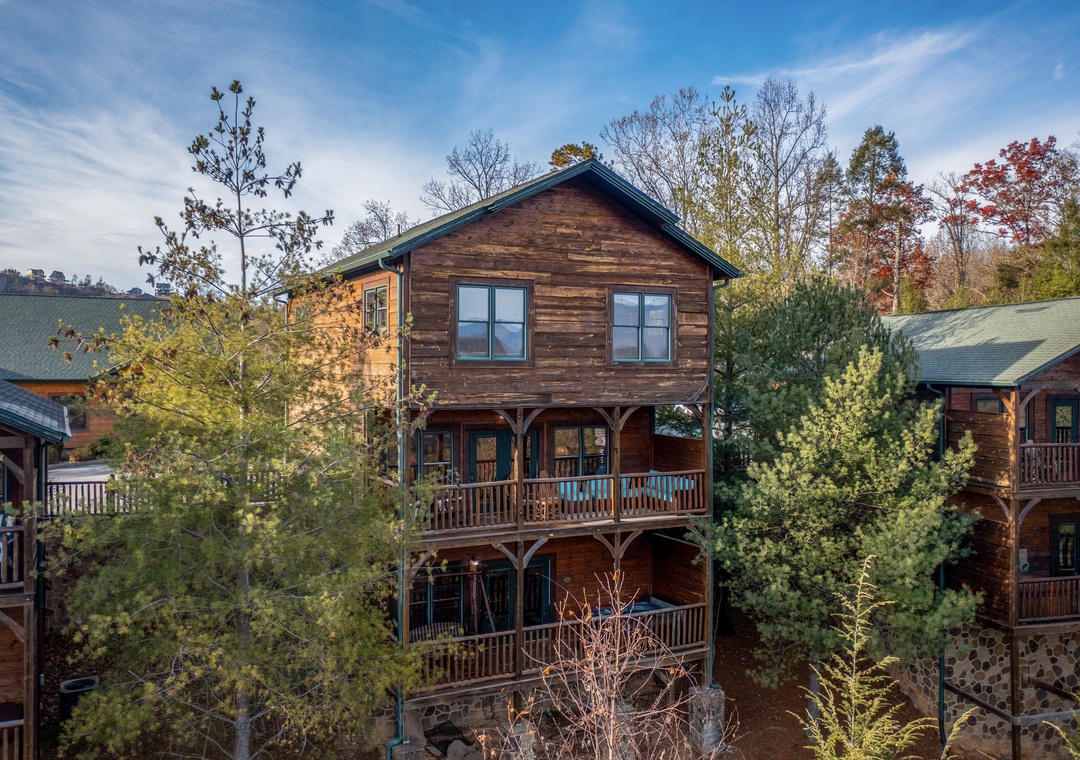 Multi-level cabin surrounded by towering pines and seasonal foliage, located in a tranquil mountain community.