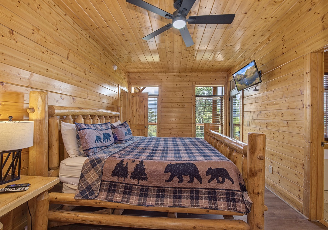 Drift off in your cozy log cabin bedroom, where rustic charm meets modern comfort beneath a gentle ceiling fan.
