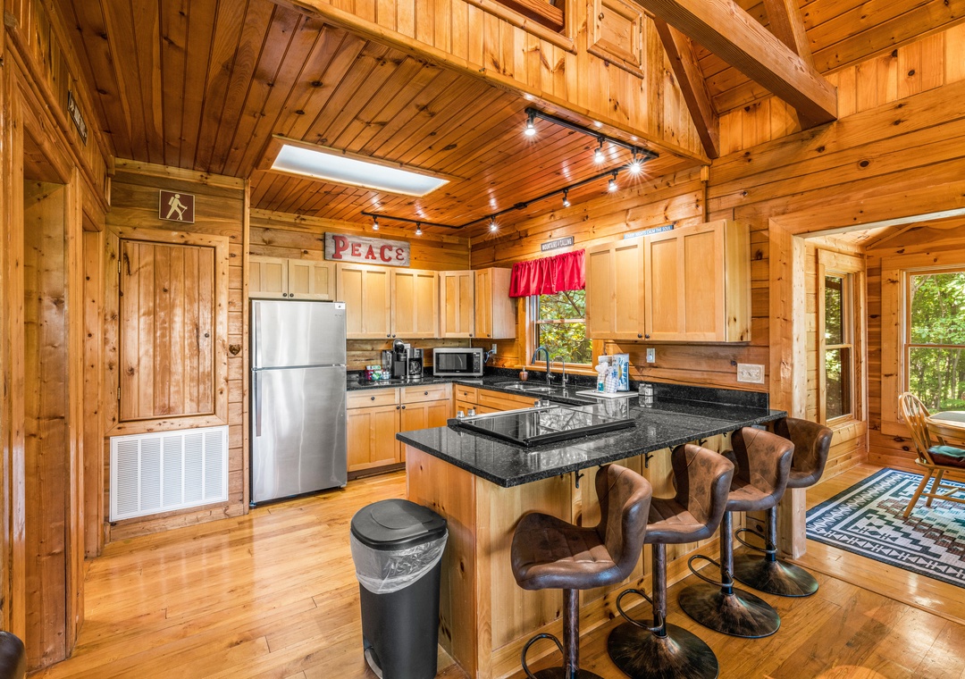 Picture yourself preparing meals in this fully equipped kitchen with granite counters, stainless appliances, and warm wood finishes throughout. The vaulted ceiling and track lighting create an inviting space where your group can gather.