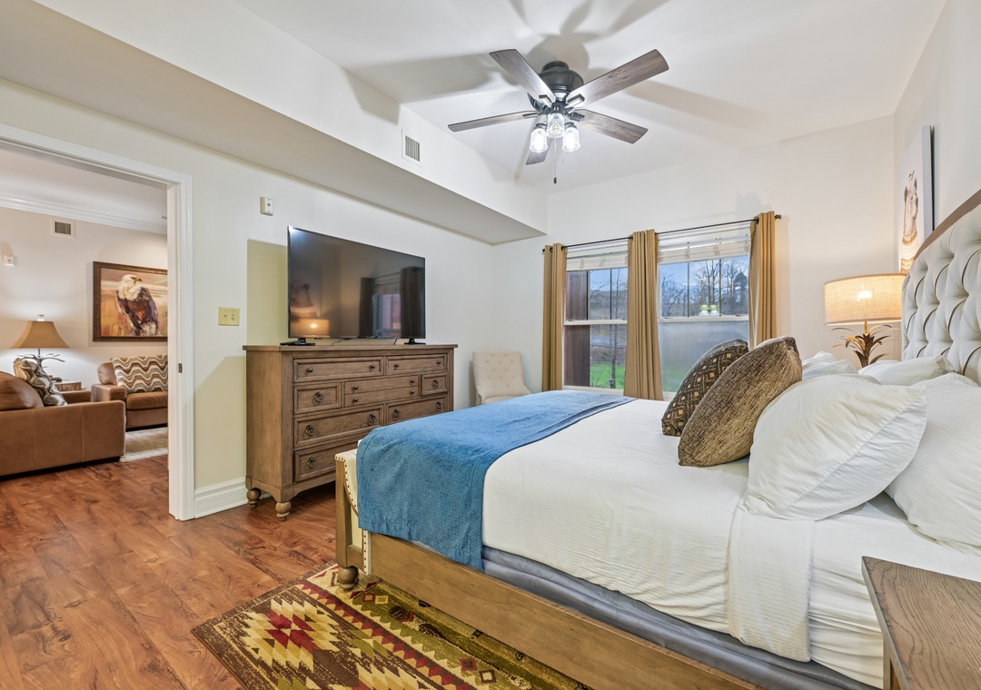 Your spacious bedroom features a plush king bed with crisp linens, ceiling fan, and charming natural light from large windows.