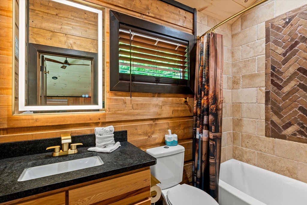 A modern bathroom blending warm wood tones with elegant stone textures. Refresh under the rainfall showerhead, unwind in the tub, and enjoy thoughtful touches like fresh towels and soft lighting.