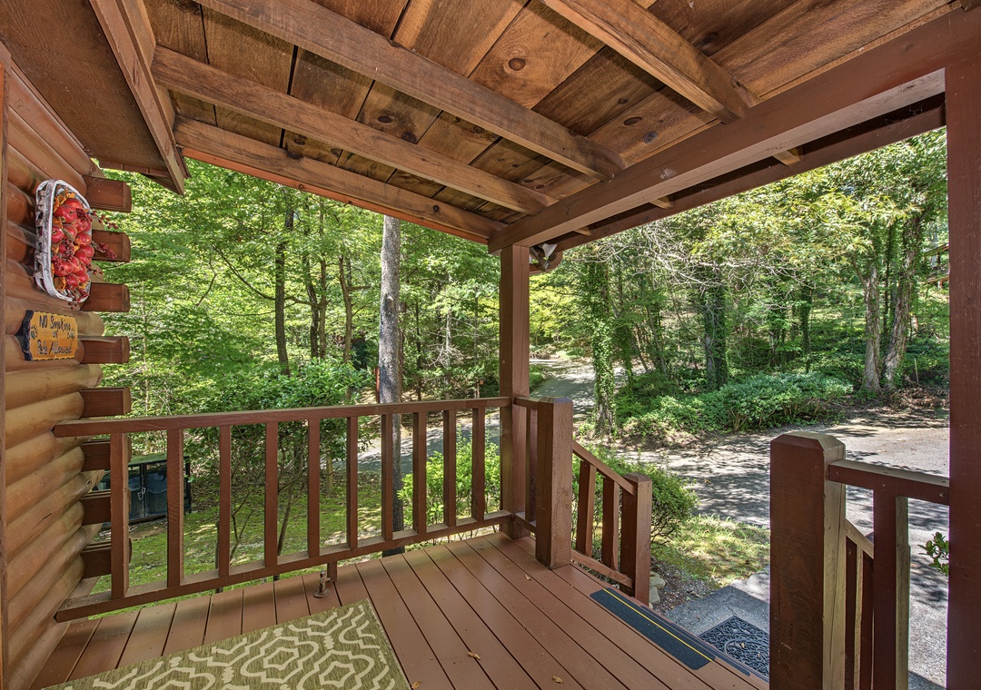 A charming covered porch welcomes you to this cozy cabin retreat, surrounded by lush forest scenery and peaceful natural surroundings.