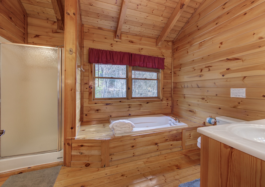 Unwind in your rustic bathroom featuring a deep soaking tub with forest views and separate shower.