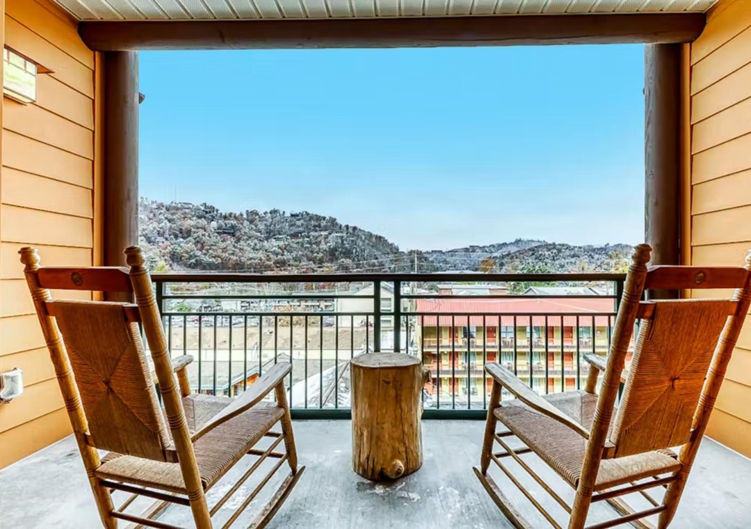 Soak in stunning mountain views from your private balcony, where rustic wooden chairs invite peaceful morning coffee moments.