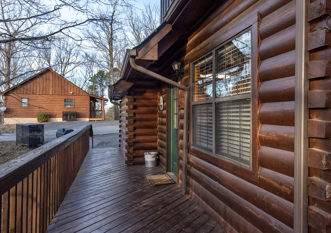 Charming log cabin exterior showcases rustic architecture with natural wood construction and covered deck area surrounded by peaceful wooded setting.