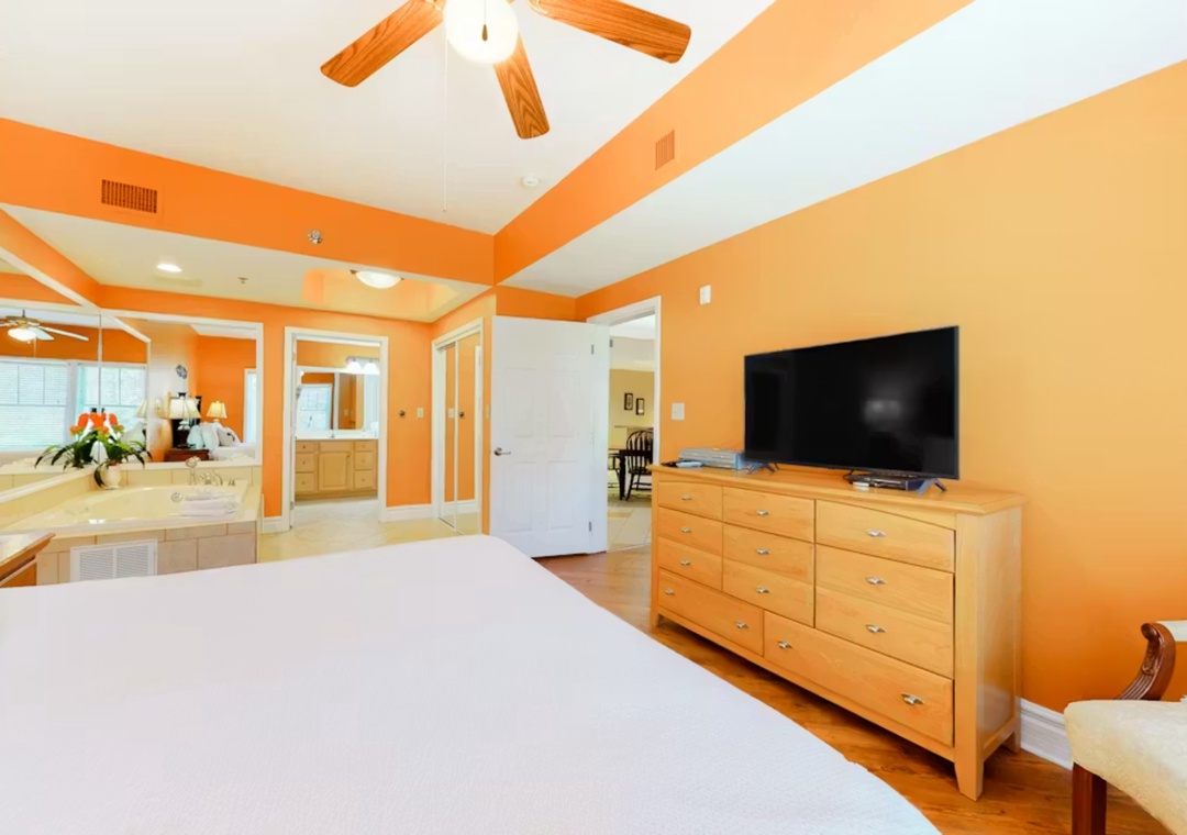 Relax in your bright master suite with warm orange walls, wooden ceiling beams, and your own TV entertainment center.