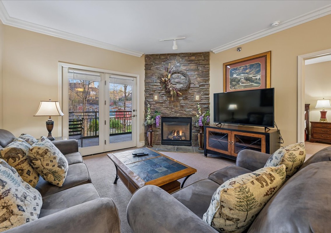 Cozy up by your stone fireplace while enjoying mountain views from your private balcony in this inviting living space.