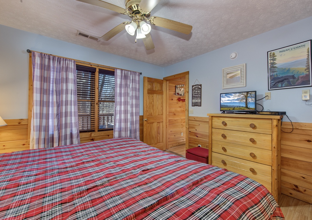 Cozy mountain bedroom featuring rustic pine furnishings, plaid bedding, and your own TV for relaxing evenings after adventure-filled days.