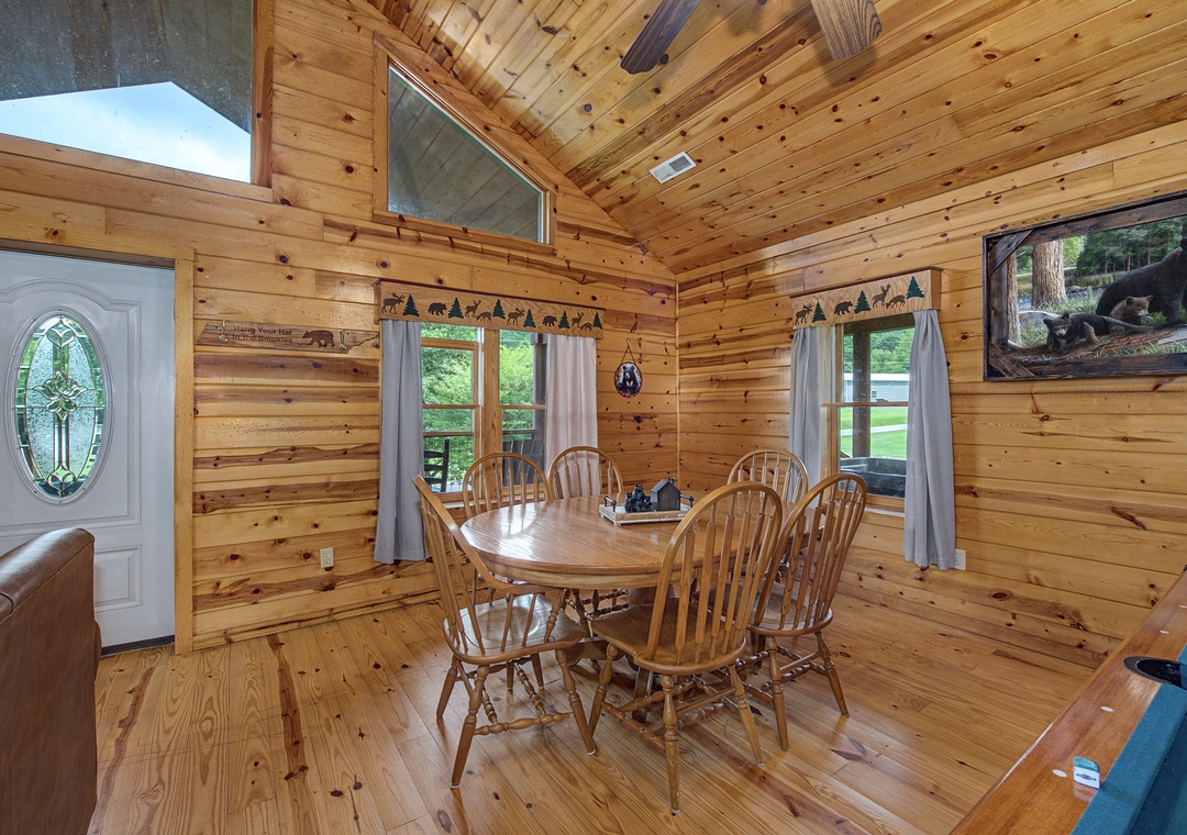Step into a warm, wood-wrapped cabin where rustic charm meets homey comfort. Sunlight streams through tall windows, highlighting the handcrafted dining table perfect for your morning coffee or family game nights.