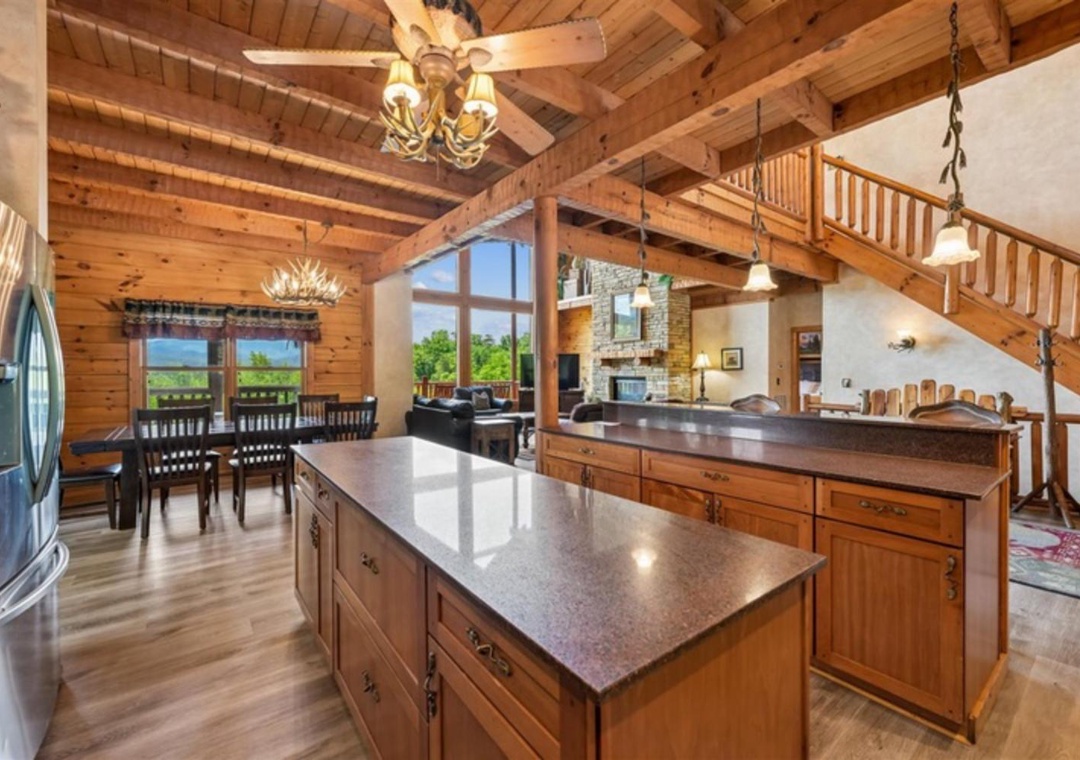 Stunning vaulted ceilings and warm wood beams frame your spacious open living area, where sunlight streams through expansive windows. Your fully-equipped kitchen awaits culinary adventures, while cozy dining and lounging spaces invite memorable gatherings