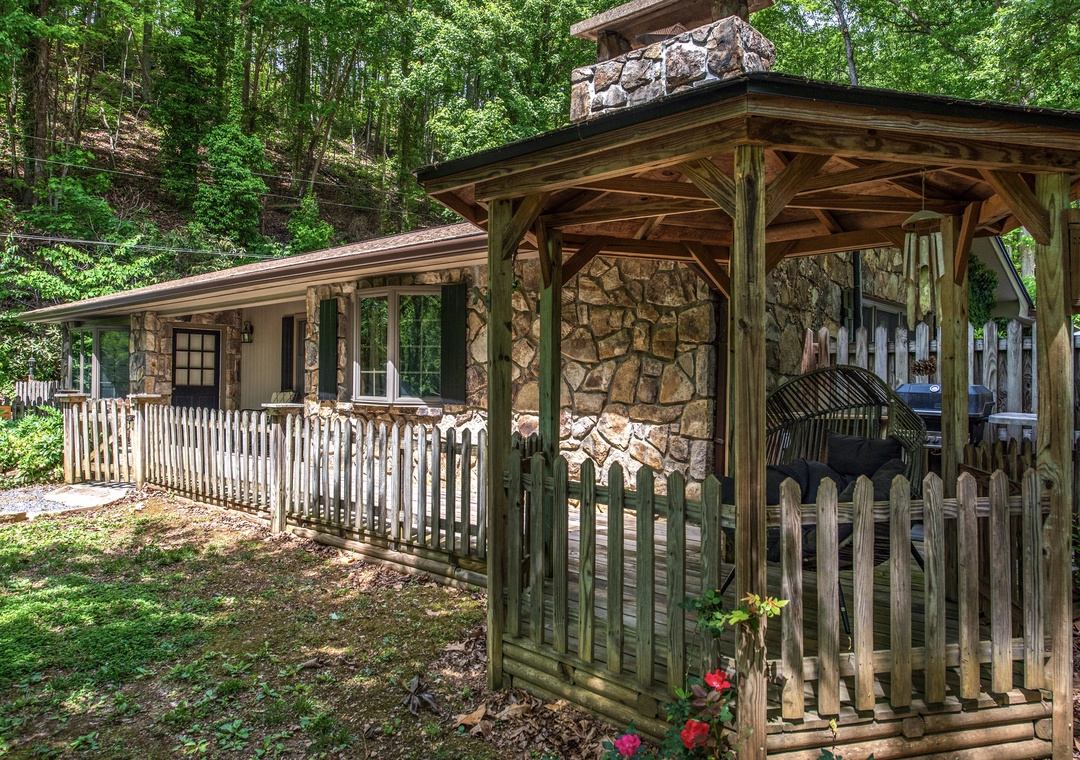 Charming stone cottage nestled in lush forest setting with private gazebo and covered BBQ area, offering rustic mountain retreat ambiance.
