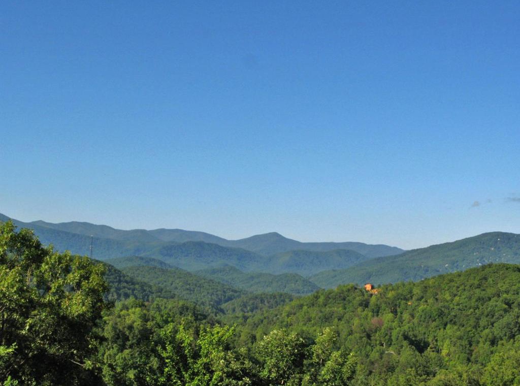 Rolling mountain ridges stretch endlessly under clear blue skies, creating a breathtaking natural backdrop for this peaceful retreat location.