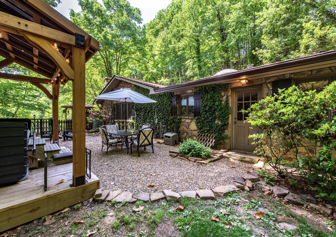 A tranquil woodland retreat with charming stone facade, ivy-draped walls, and secluded patio for peaceful mornings nestled among the trees.
