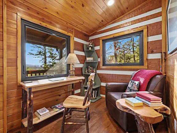 Curl up in this cozy reading nook with warm wood walls, comfortable seating, and stunning mountain views framed by picture windows—your perfect retreat for relaxation.