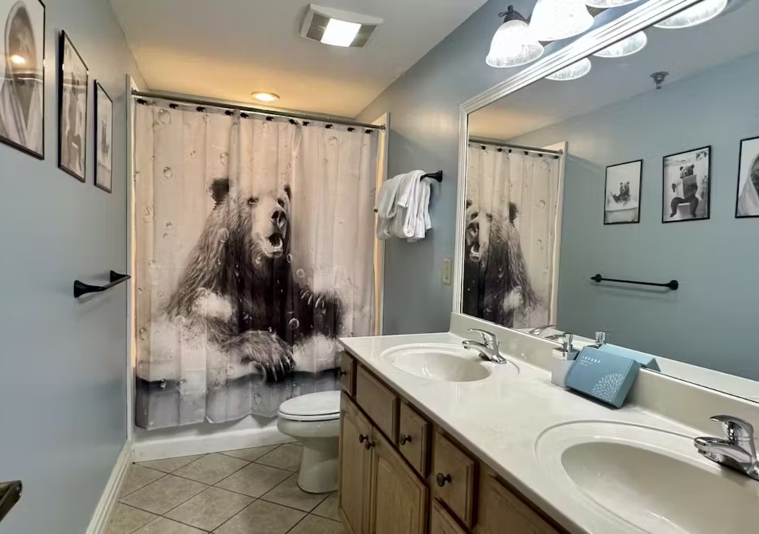Relax in your spacious private bathroom featuring dual sinks, ample counter space, and charming bear-themed decor that adds whimsical character to your stay.
