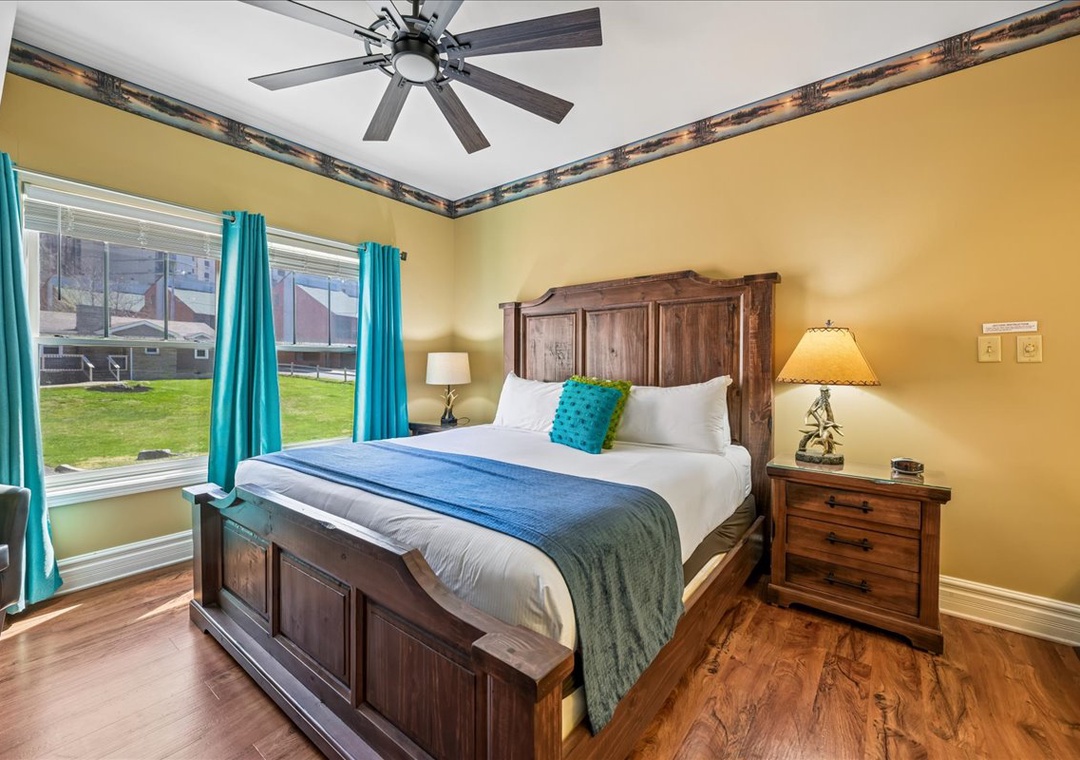 Relax in your cozy bedroom featuring rustic wood furniture, cheerful turquoise accents, and a ceiling fan for comfort.