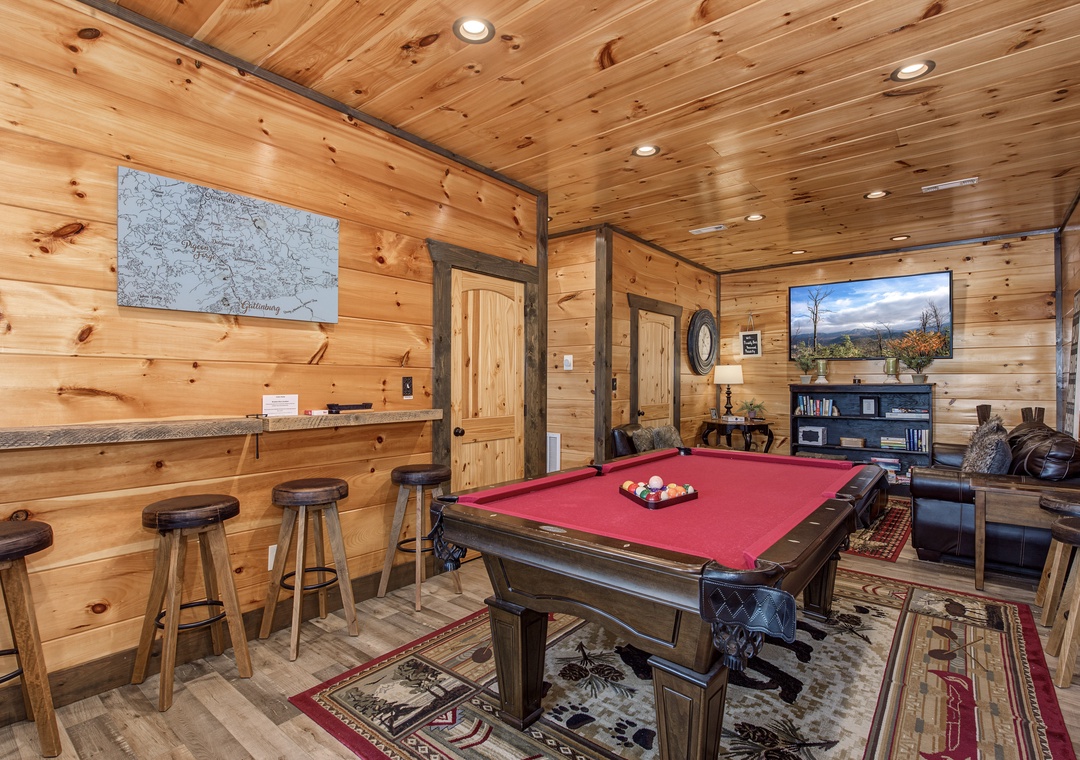 Challenge your friends at the pool table in this cozy game room with warm wood accents, a wet bar, big-screen TV, and rustic mountain charm.