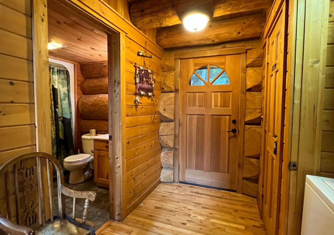 Step into your warm, rustic retreat where natural wood walls and beamed ceilings welcome you with authentic cabin charm. The welcoming entryway leads to your private spaces, wrapped in golden tones that make every moment feel cozy and secluded.