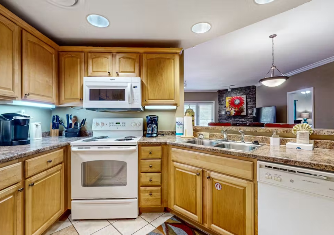 Prepare your favorite meals in this fully equipped kitchen featuring warm wood cabinets, granite countertops, and modern appliances.