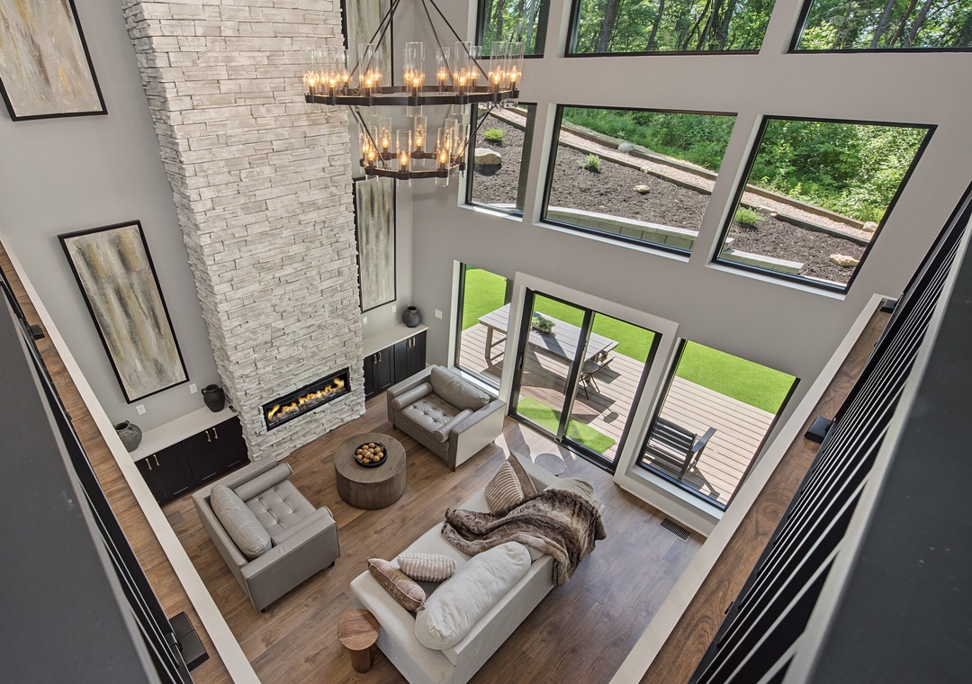 Soaring ceilings and expansive windows frame your private retreat, where a statement chandelier illuminates modern comforts and a cozy fireplace anchors this elegant living space.