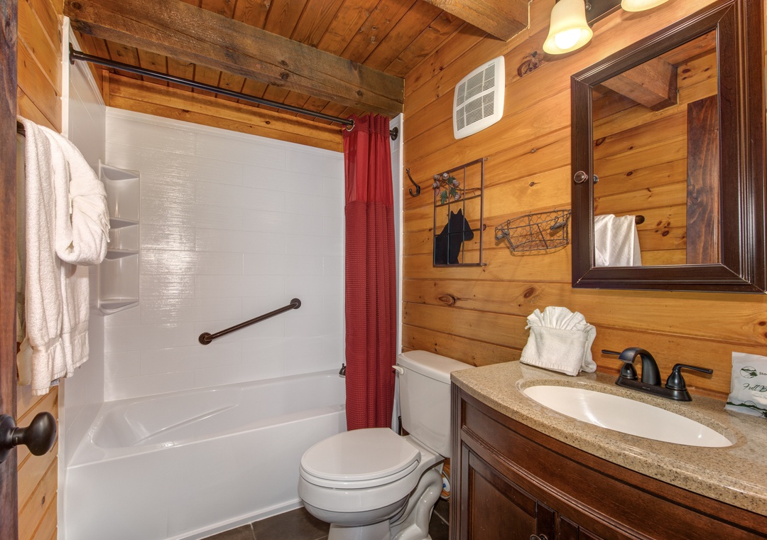 Unwind in your cozy log cabin bathroom featuring warm wood walls, granite countertops, and a soothing tub-shower combo.