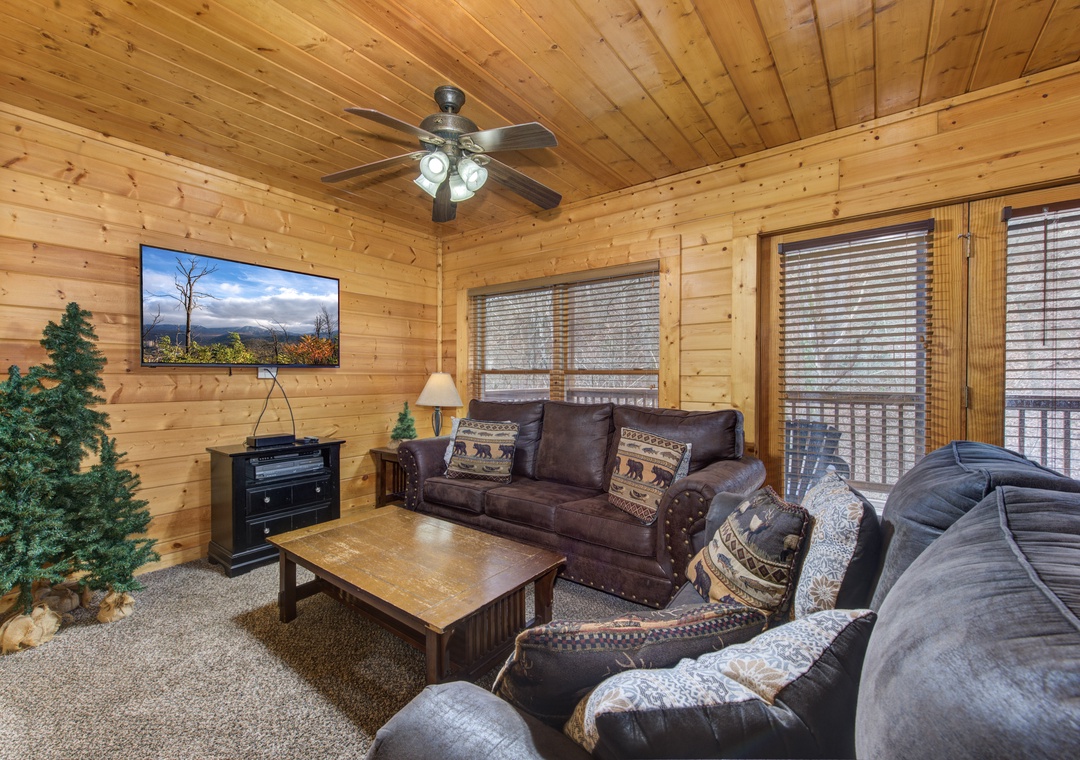 Unwind in your cozy living room with rustic wood walls, plush seating, and mountain views on the big screen TV.