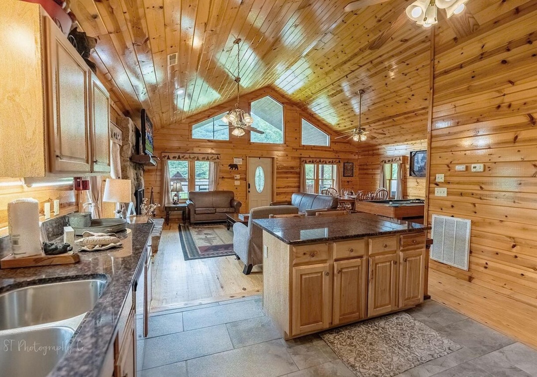 Step into your cozy cabin retreat where warm wood tones and vaulted ceilings create an inviting open-concept space. You'll find everything you need—a fully equipped kitchen, comfortable living area, and natural light streaming through cathedral windows.