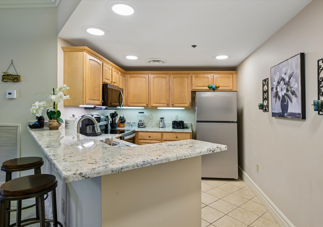Your spacious kitchen invites culinary adventures with gleaming granite counters, stainless appliances, and warm wood cabinetry—perfect for preparing meals or sharing morning coffee at the breakfast bar.