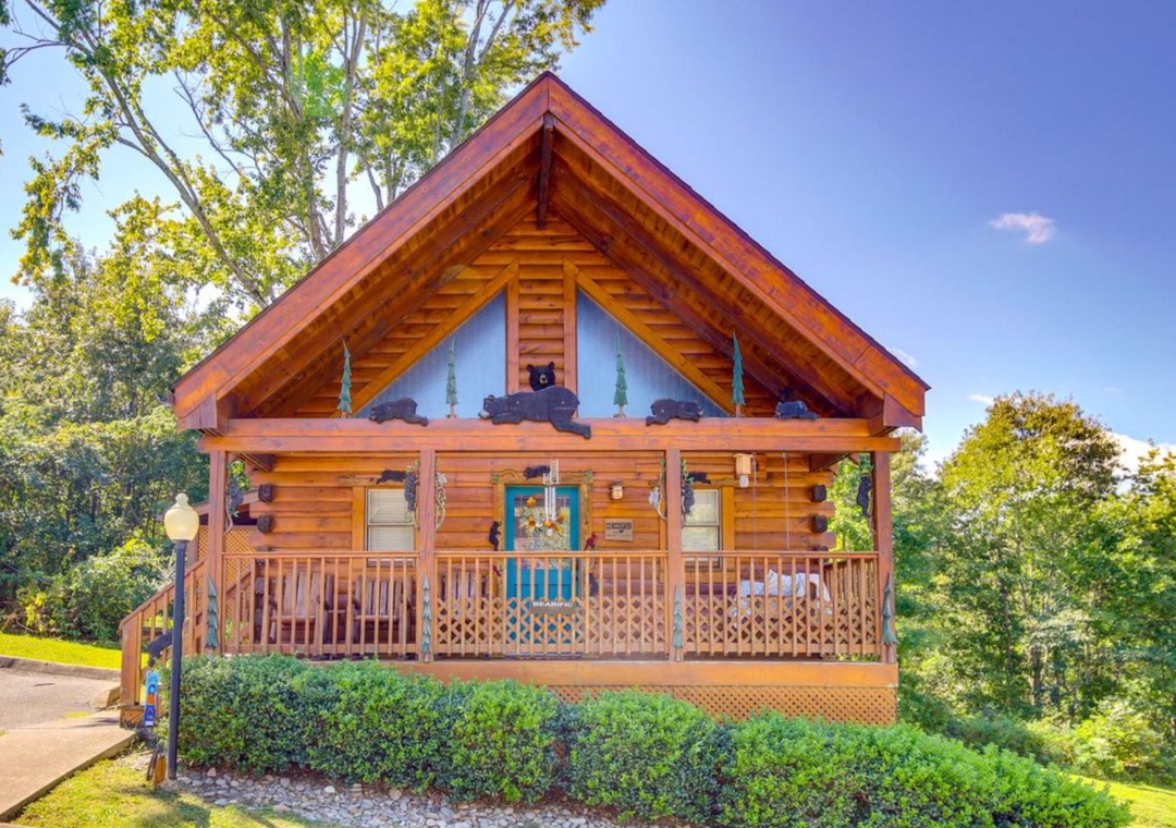 Charming log cabin retreat with covered porch and rustic mountain charm, nestled among towering trees.