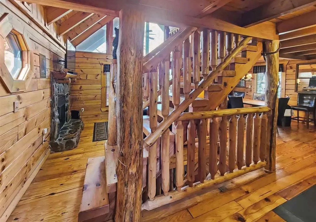 Step into rustic charm with handcrafted log stairs and cozy stone fireplace creating your perfect mountain retreat atmosphere.