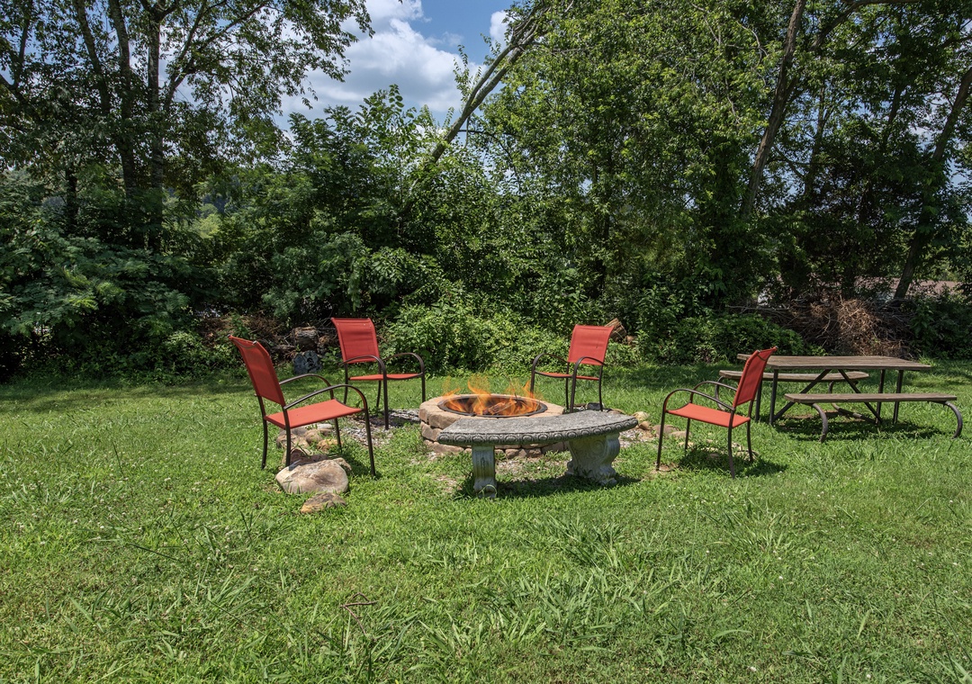 This private outdoor area features a stone fire pit surrounded by comfortable seating, perfect for unwinding beneath the trees after an active day exploring nearby trails.