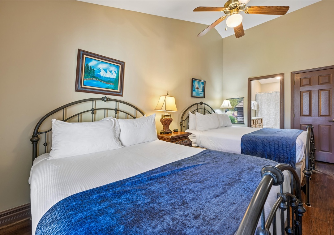 Relax in your cozy twin bedroom featuring comfortable beds with crisp linens and warm mountain artwork above.