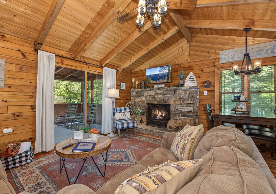 Curl up beside the glowing stone fireplace in your cozy cabin retreat. Natural wood surrounds you, while large windows invite forest views inside. This space feels like your own mountain sanctuary.