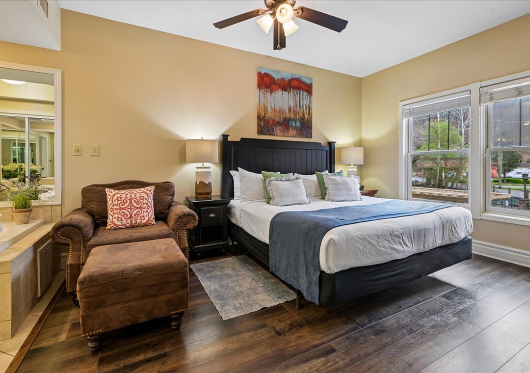 Unwind in your spacious bedroom featuring a plush king bed, cozy reading chair, and peaceful street views through large windows.