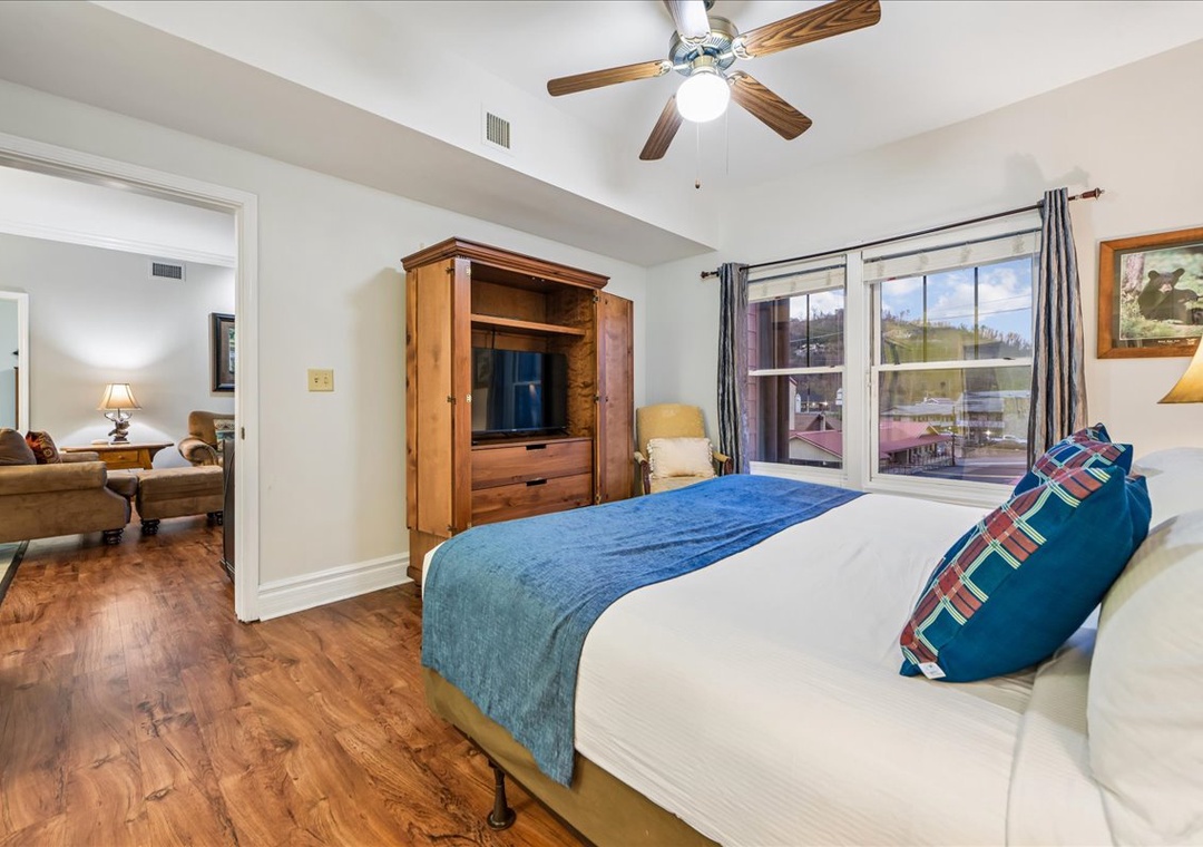 Sink into your comfortable bed with crisp linens and enjoy the ceiling fan's gentle breeze while watching TV from the wooden entertainment center.