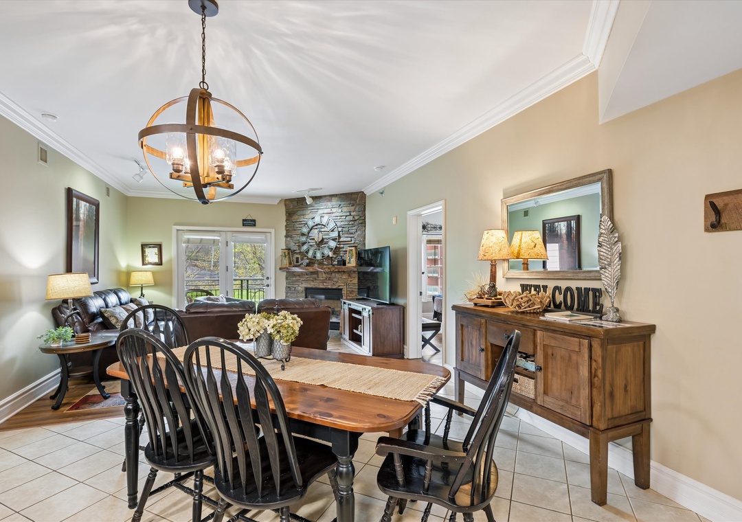 Gather around your elegant dining table where rustic charm meets comfort beneath warm lighting and stone fireplace ambiance.