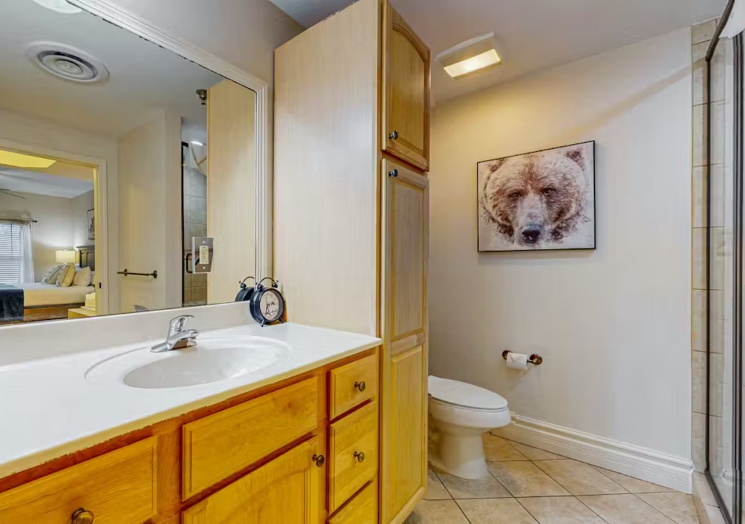Your private bathroom features a spacious vanity with ample storage, clean tile floors, and charming bear artwork that adds local mountain character.