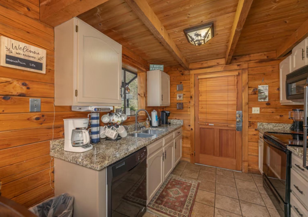 Your fully equipped kitchen blends rustic charm with modern convenience, featuring granite countertops, warm wood beams, and everything you need to prepare meals in your mountain retreat.