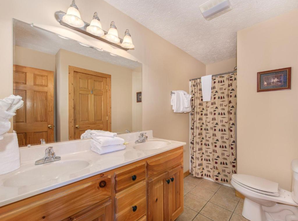 Your bathroom features rustic wood vanity, fresh towels, and charming mountain-themed shower curtain for cozy comfort.