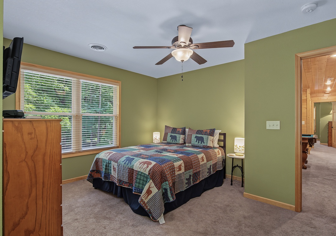 Relax in your peaceful bedroom with a comfy bed, calming green walls, and a ceiling fan to keep you cool. Natural light and warm wood touches create a cozy retreat for restful nights.