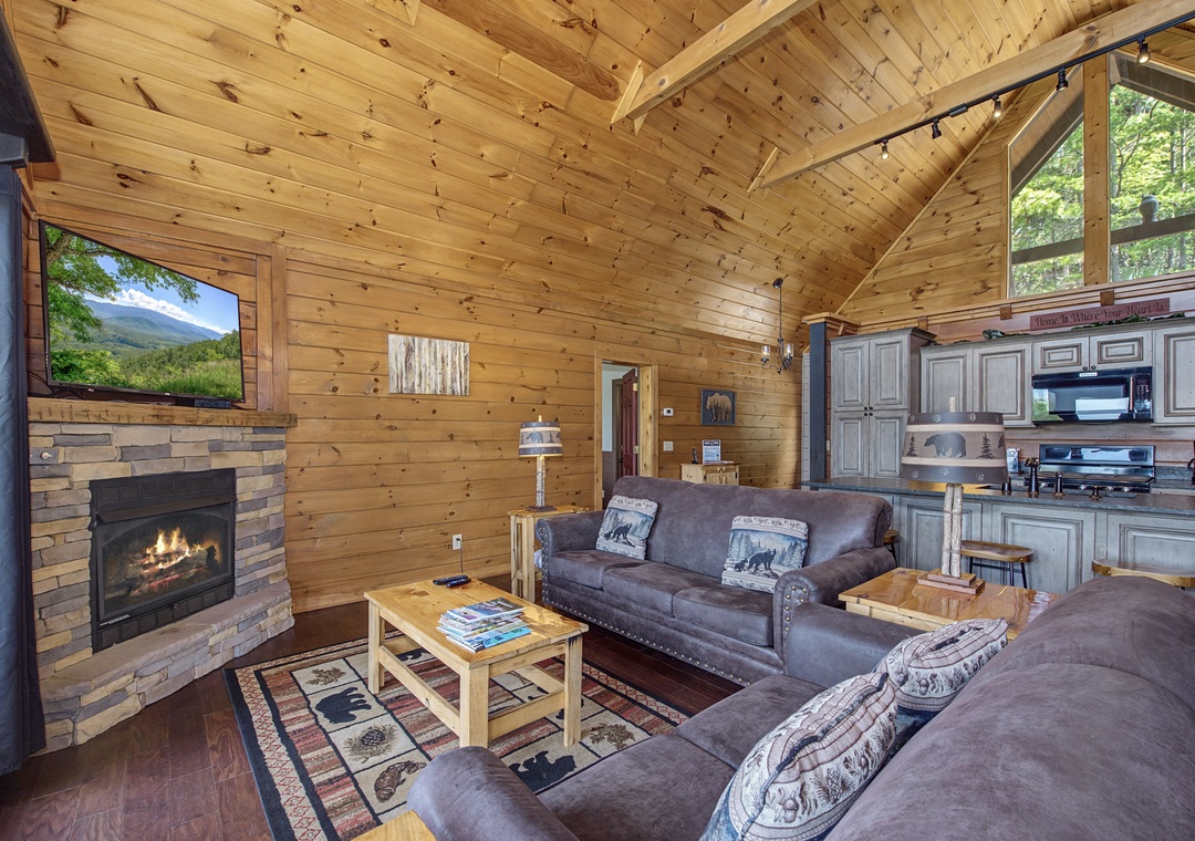 Cozy up in this rustic cabin living room with crackling fireplace, mountain views, and comfortable leather seating perfect for relaxing evenings.