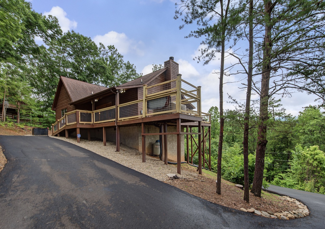 A rustic mountain cabin nestled among tall pines and lush greenery, offering a secluded retreat with convenient parking and private decking for outdoor relaxation.