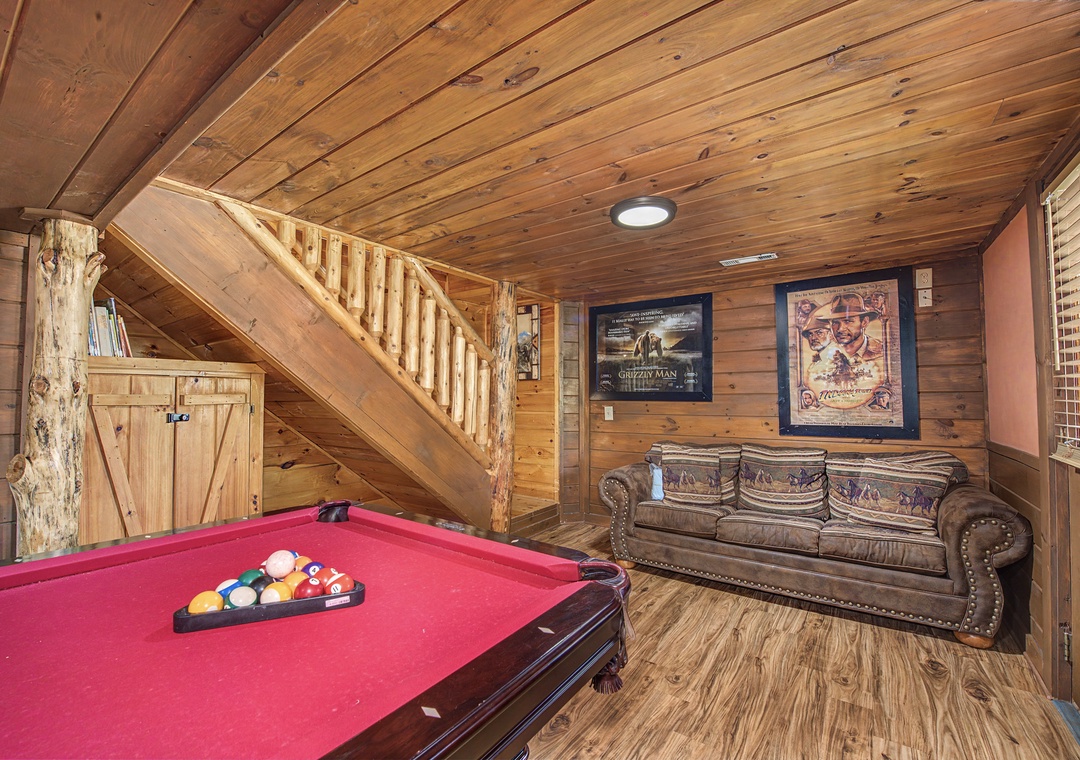 Rustic game room with red felt pool table and cozy leather sofa where you'll enjoy friendly competition.
