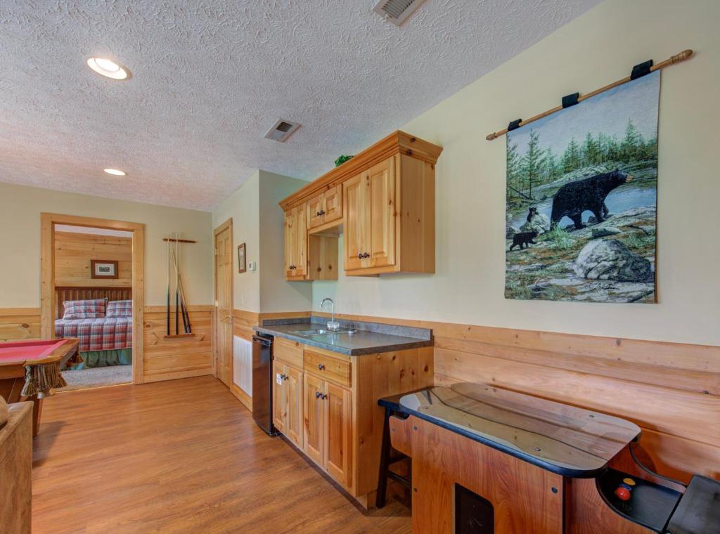 Rustic knotty pine kitchen with granite counters and wilderness artwork creates your cozy mountain retreat atmosphere.