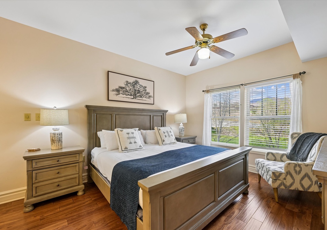 Unwind in your peaceful bedroom featuring elegant furnishings, ceiling fan for comfort, and natural light streaming through large windows.